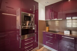 Eine moderne Küche mit Edelstahlgeräten, darunter eine Mikrowelle und ein Backofen, sowie violetten Schränken.
