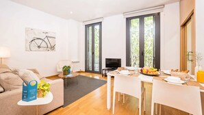 Un salon moderne comprenant un canapé, une table basse, une table à manger pour deux personnes et un téléviseur.