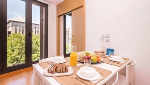 Una mesa con platos, cubiertos y una variedad de frutas, además de un vaso de jugo de naranja.