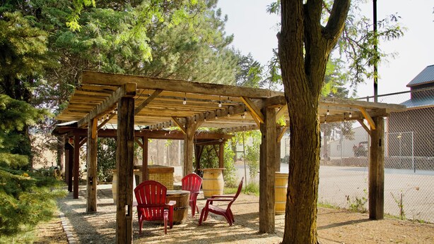 Un espacio de estar al aire libre techado, con vigas de madera y sillas rojas.