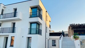 Ein modernes, mehrgeschossiges Gebäude mit Balkonen, einer Treppe und Sitzgelegenheiten im Freien.