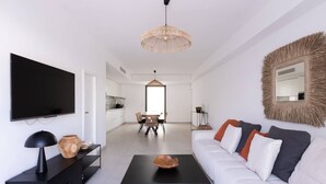 Ein modernes Wohnzimmer mit einem schwarzen Couchtisch, einem weißen Sofa und einem großen Flachbildfernseher an der Wand.