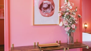 A pink-themed room with a wooden desk, two red mesh chairs, a framed artwork, and a vase with flowers. - 🍷🌇  All Day & Night!  BEST EAST NASH location - Walkable (Nashville)