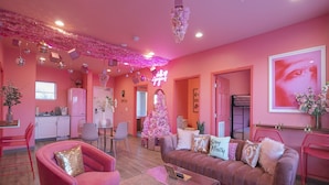 A pink-themed living room with a sofa, chairs, and a Christmas tree. - 🍷🌇  All Day & Night!  BEST EAST NASH location - Walkable (Nashville)
