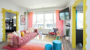 A modern living room with a pink sofa, a coffee table, and a TV mounted on the wall. - 🎸🎇 CLUELESS HOME IN NASH-VEGAS! WALKABLE LOCATION! (Nashville)
