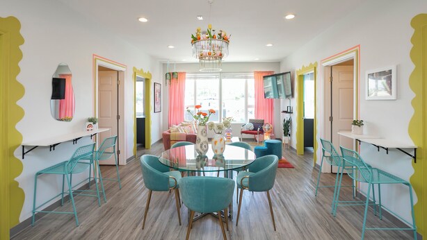 A modern dining area with a glass table, teal chairs, and a central floral chandelier. - 🎸🎇 CLUELESS HOME IN NASH-VEGAS! WALKABLE LOCATION! (Nashville)