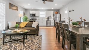 A modern living room with a sofa, coffee table, and dining area with chairs.