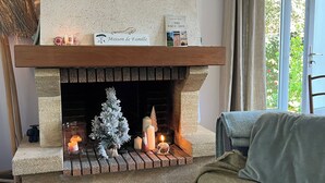 A fireplace with a mantel shelf, a small Christmas tree, candles, and a sign reading 'Maison de Famille.' - Maison Proche de la Plage (Pornic)