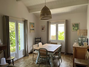 Zona pranzo con tavolo, sedie, lampadario e finestra con tende.