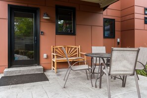 Un patio al aire libre con un banco de madera, sillas de metal y una mesa.