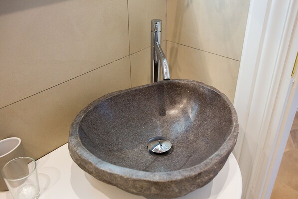 A stone sink with a modern faucet in a bathroom. - Bramble Luxury Suites (Rome)