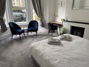 A hotel room with a large bed, two armchairs, a desk, and a fireplace. - 2-bed, Sleeps 4, Free Parking, Pets Allowed (Eastbourne)