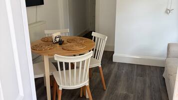 A dining area with a round table, white chairs, and a dark wooden floor.