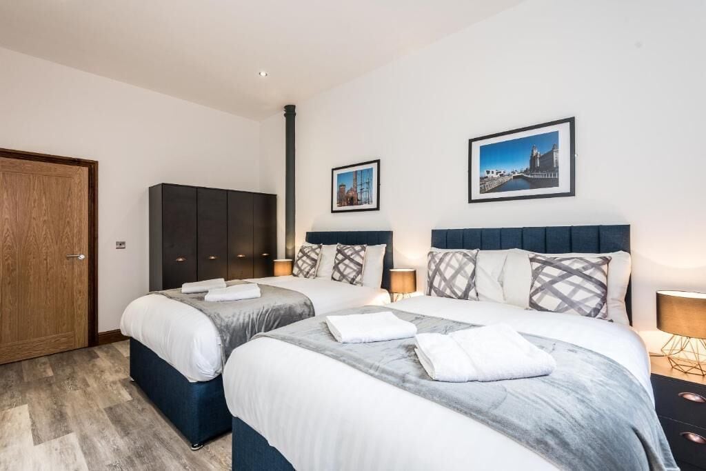 Une chambre d’hôtel avec deux lits, une armoire et deux tableaux encadrés au mur.