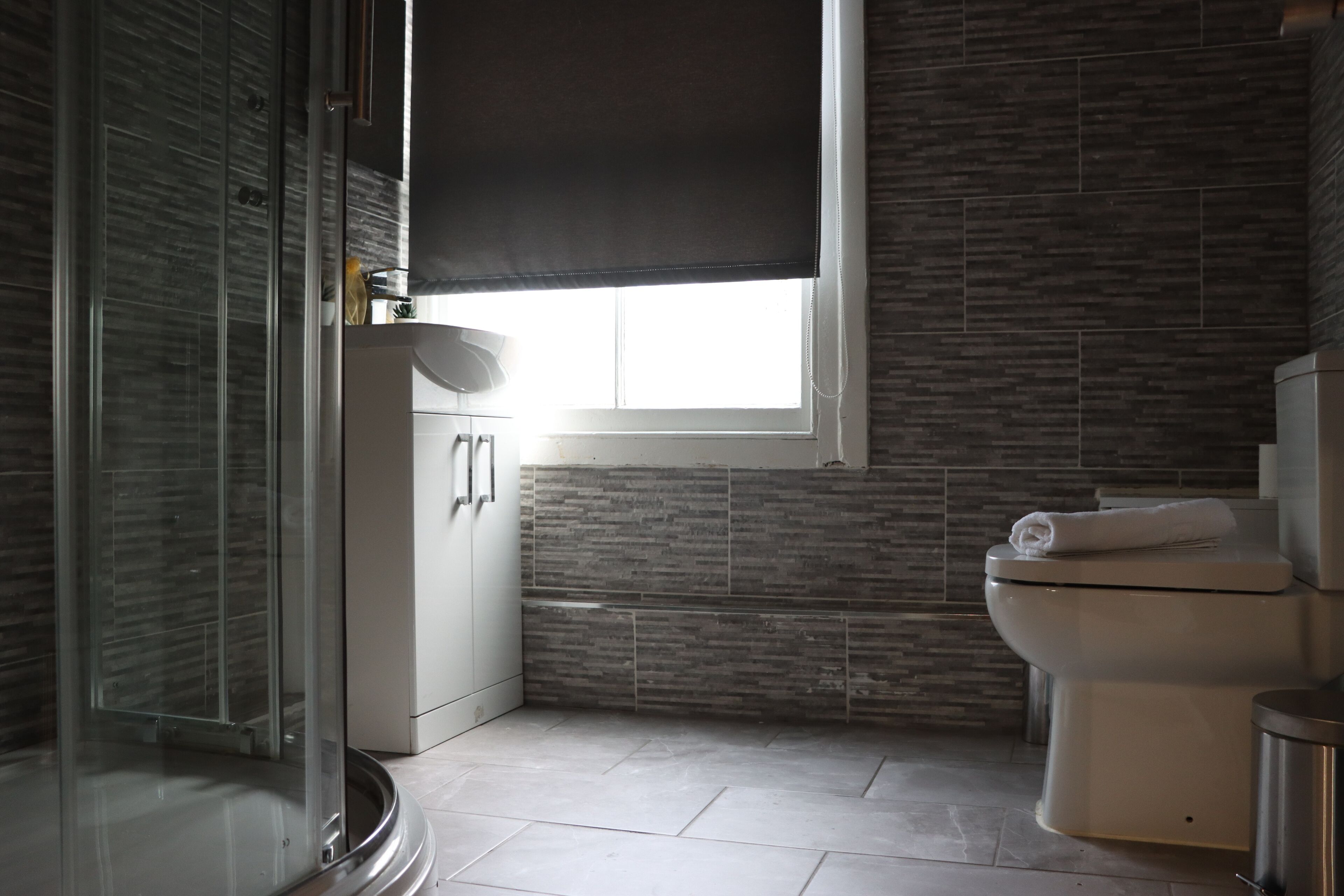 A bathroom with a shower, toilet, and sink.