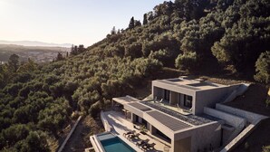 Una villa moderna con piscina, immersa in una fitta foresta e colline.