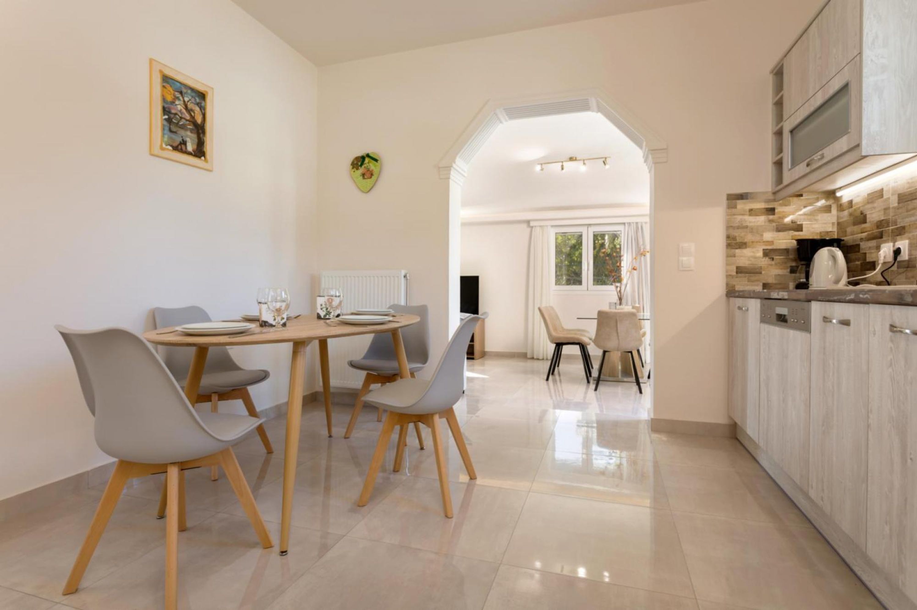 Eine moderne Küche mit Essbereich, ausgestattet mit einer Kochinsel, Stühlen und Blick in den Esszimmer.