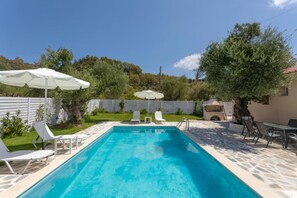 A rectangular swimming pool with clear blue water, surrounded by white lounge chairs and umbrellas. - Michaelo Villa - Affordable Luxury - Michaelo Villa - Affordable Luxury (Zakynthos)