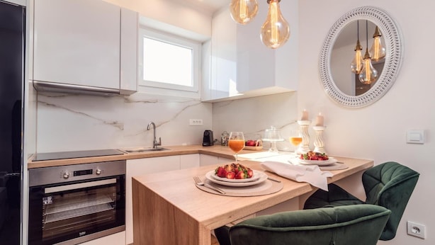 Une cuisine moderne dotée d’un four encastré, d’un plan de travail en bois et d’un coin repas avec une chaise recouverte d’un tissu vert.
