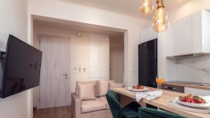 Une cuisine moderne avec un coin repas, un téléviseur à écran plat fixé au mur et une table à manger en bois avec des chaises.