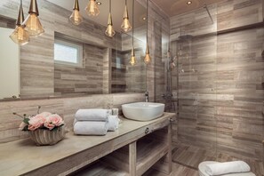 Ein modernes Badezimmer mit einem Holzbadschränkchen, einem großen Spiegel und einer Duschkabine aus Glas.