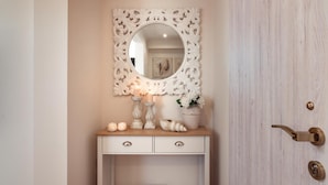 Une coiffeuse blanche avec un miroir, une bougie et des objets décoratifs.