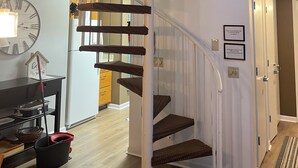 Um interior moderno com escada em espiral, um relógio de parede grande e uma área de estar aconchegante.