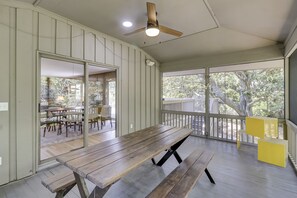 Enjoy al fresco dining in this serene outdoor space with a picnic table and benches, surrounded by a railing and ceiling fan.