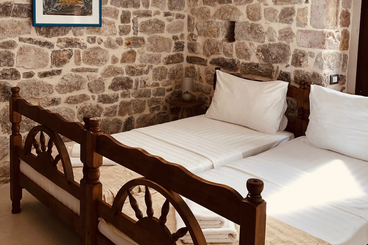 Une chambre avec un mur en pierre, un cadre de lit en bois et une lucarne.