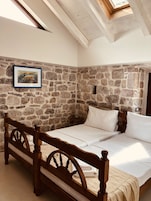 Un dormitorio con pared de piedra, estructura de cama de madera y tragaluz.