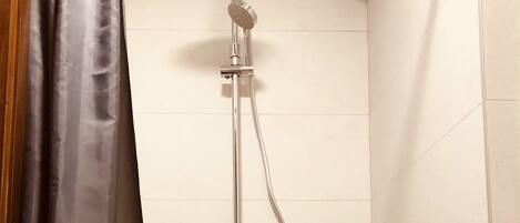 A shower with a handheld showerhead and a handheld faucet.