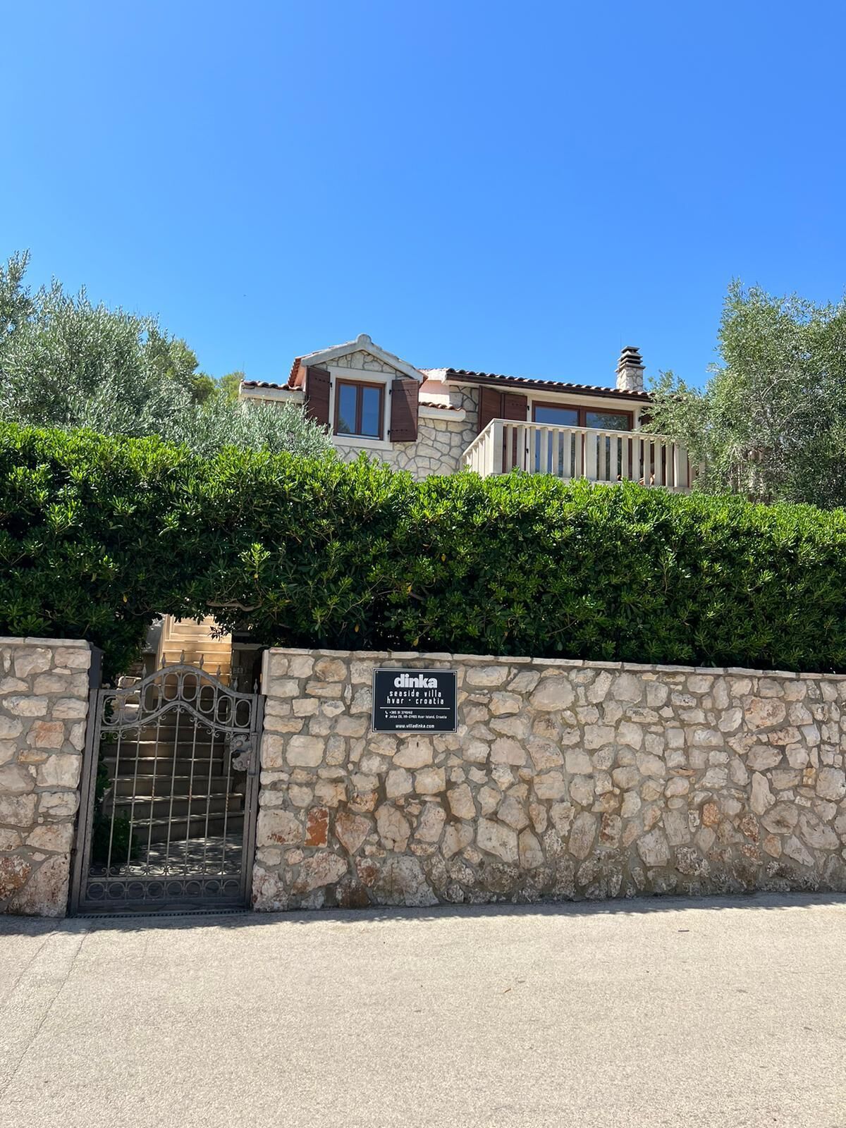 A stone wall with a metal gate and a sign indicating a seaside villa in Croatia.