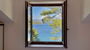 A bedroom with a window overlooking a body of water and trees.