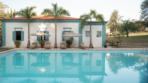 A poolside area with a pool, lounge chairs, and umbrellas.