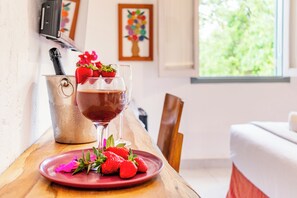 A dining table with a glass of red wine, strawberries, and a red plate. - Limoeiro Da Concordia Hotel Fazenda De Charme (Itu)