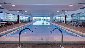 A pool area with a clear view of the pool, lounge chairs, and tables.
