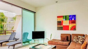 Una sala de estar moderna con un separador de vidrio, un televisor de pantalla plana, un sofá marrón y un cuadro abstracto lleno de color.