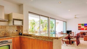 Una cocina moderna con encimeras de granito, armarios de madera, microondas integrado y un comedor con mesa y sillas.