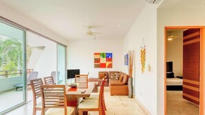 Una sala moderna con comedor, un sofá y una televisión.