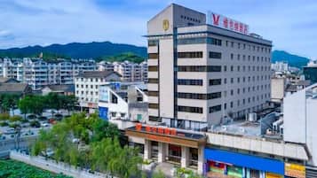 Un edificio de varios pisos con un letrero llamativo, rodeado de otros edificios y vegetación.