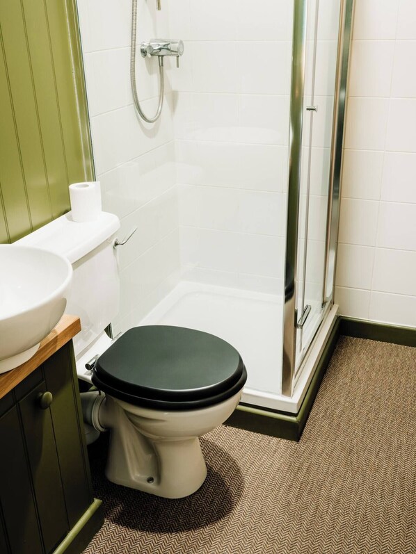 A bathroom with a toilet, sink, shower, and a herringbone-patterned floor. - Beautiful Listed Gatehouse in Great Area (Sheffield)