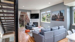 A modern living room with a grey sofa, a white coffee table, and a fireplace. - Perch - Marion Manor 13: Spacious & cozy living in the heart of Seattle (Seattle)