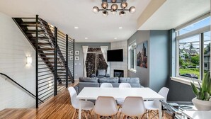 A modern living space with a staircase, a dining area, and a large window offering a view of the outside. - Perch - Marion Manor 13: Spacious & cozy living in the heart of Seattle (Seattle)