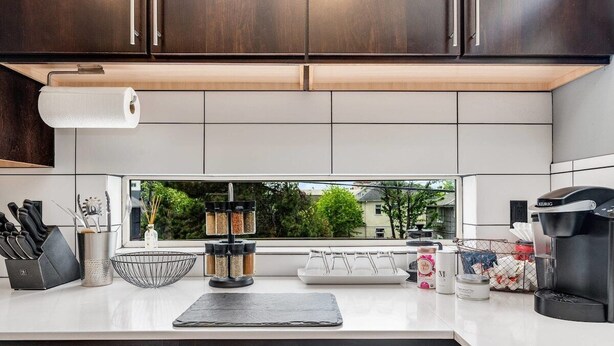 A modern kitchen with a large window, a coffee machine, and various kitchen utensils and appliances. - Perch - Marion Manor 13: Spacious & cozy living in the heart of Seattle (Seattle)