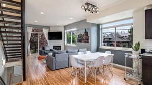 A modern kitchen with a dining area, a gray sofa, and a staircase. - Perch - Marion Manor 13: Spacious & cozy living in the heart of Seattle (Seattle)