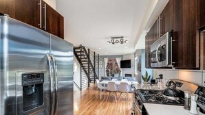 A modern kitchen with stainless steel appliances, a dining area with a staircase, and a living space with a fireplace. - Perch - Marion Manor 13: Spacious & cozy living in the heart of Seattle (Seattle)