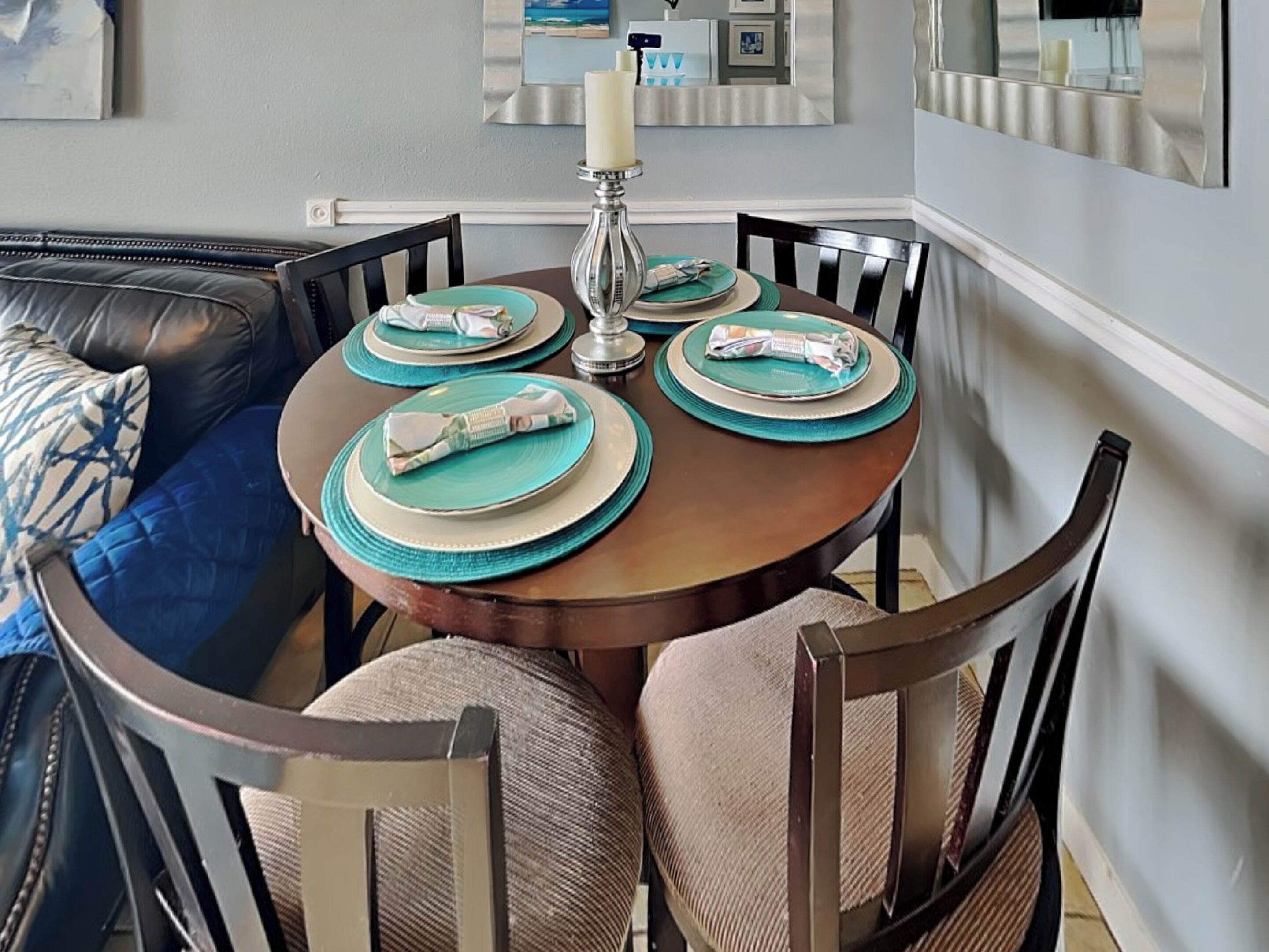 A dining table set with plates, napkins, and a candle.