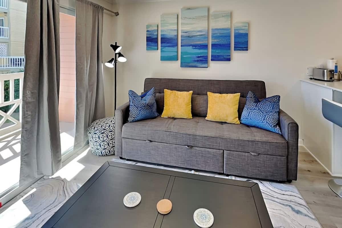A modern living room with a grey sofa, patterned cushions, and a coffee table with decorative plates.