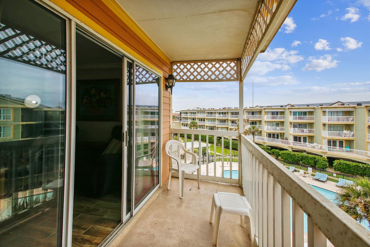 A balcony with a view of a swimming pool and adjacent buildings.