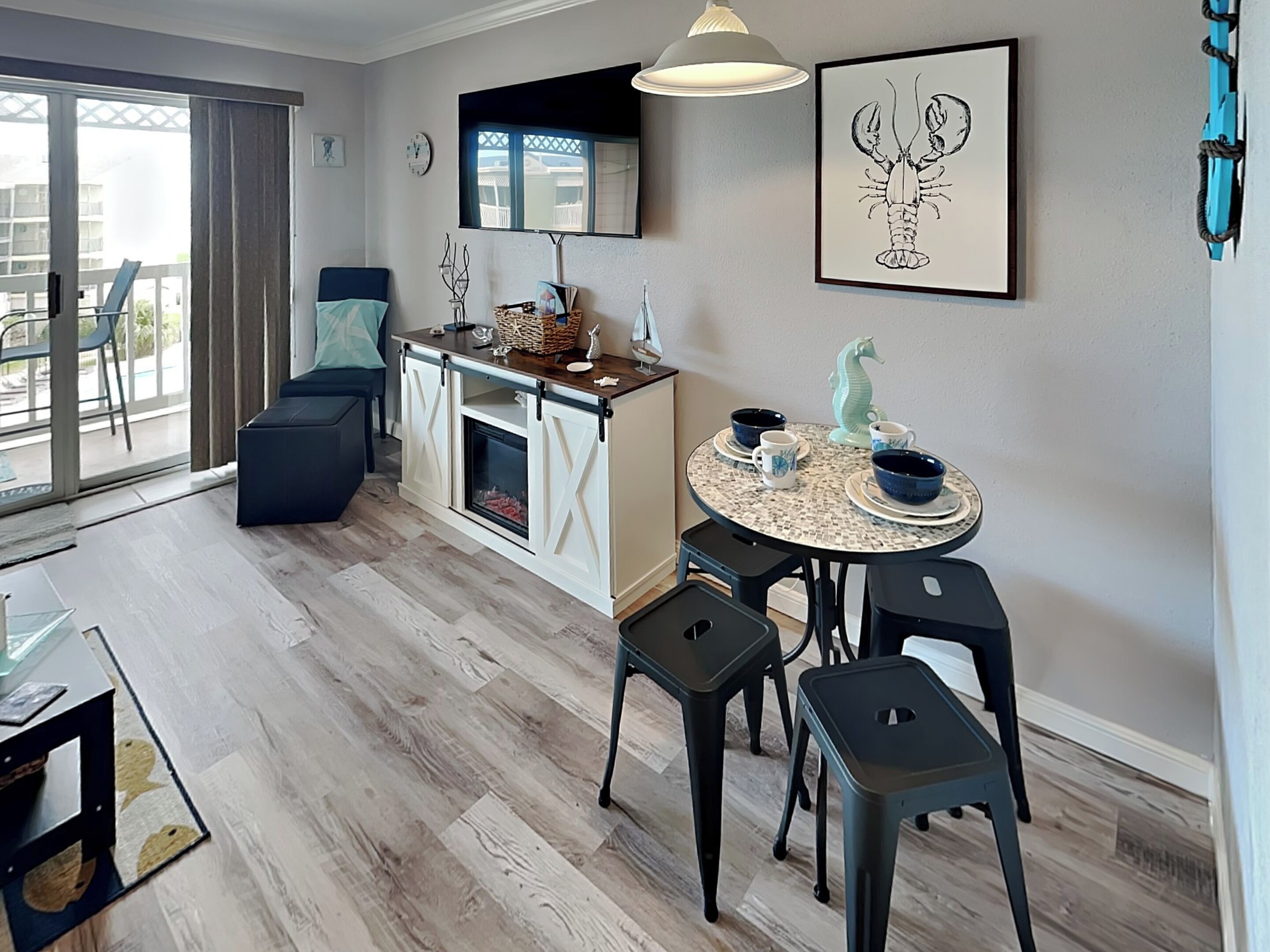 A modern kitchen with a dining area, featuring a round table with chairs, a built-in oven, and a large window with a view of the outside.
